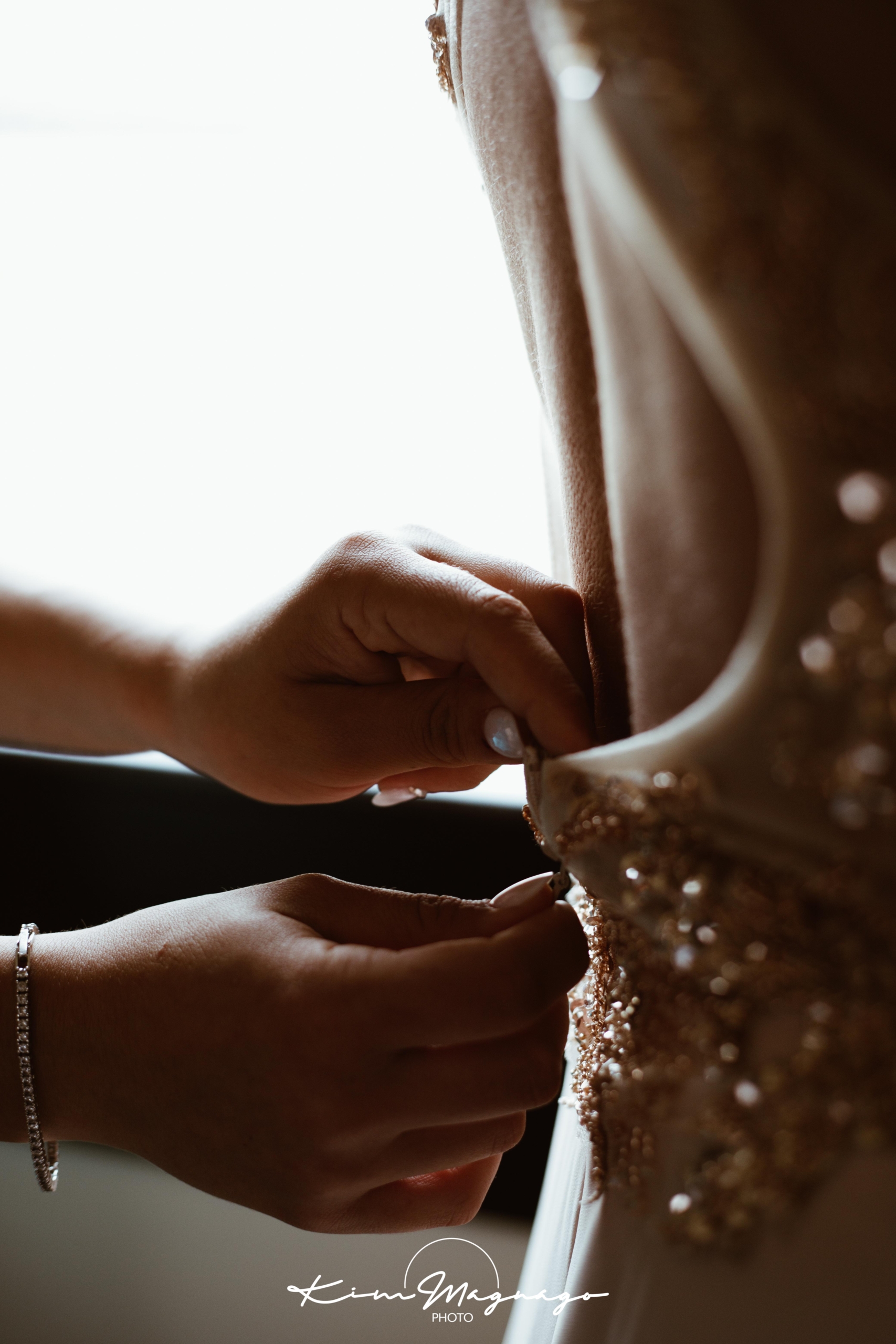 mani che chiudono l'abito il giorno del matrimonio